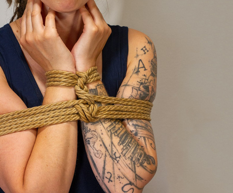 Person mit vor dem Körper gefesselten Armen 