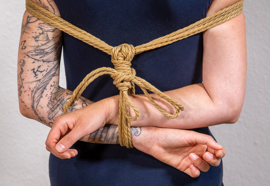 Die Arme einer Person sind auf dem Rücken in Form einer Box gefesselt. 