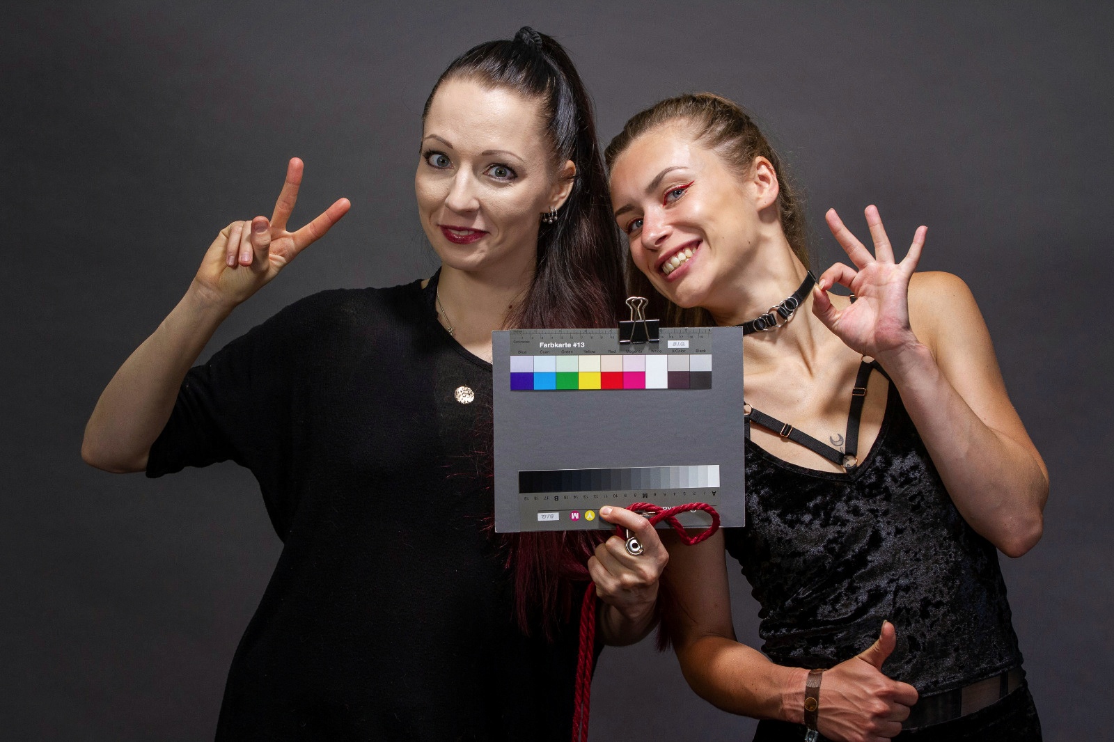 Zwei Frauen mit Filmklappe für Farbabgleich lächeln in die Kamera
