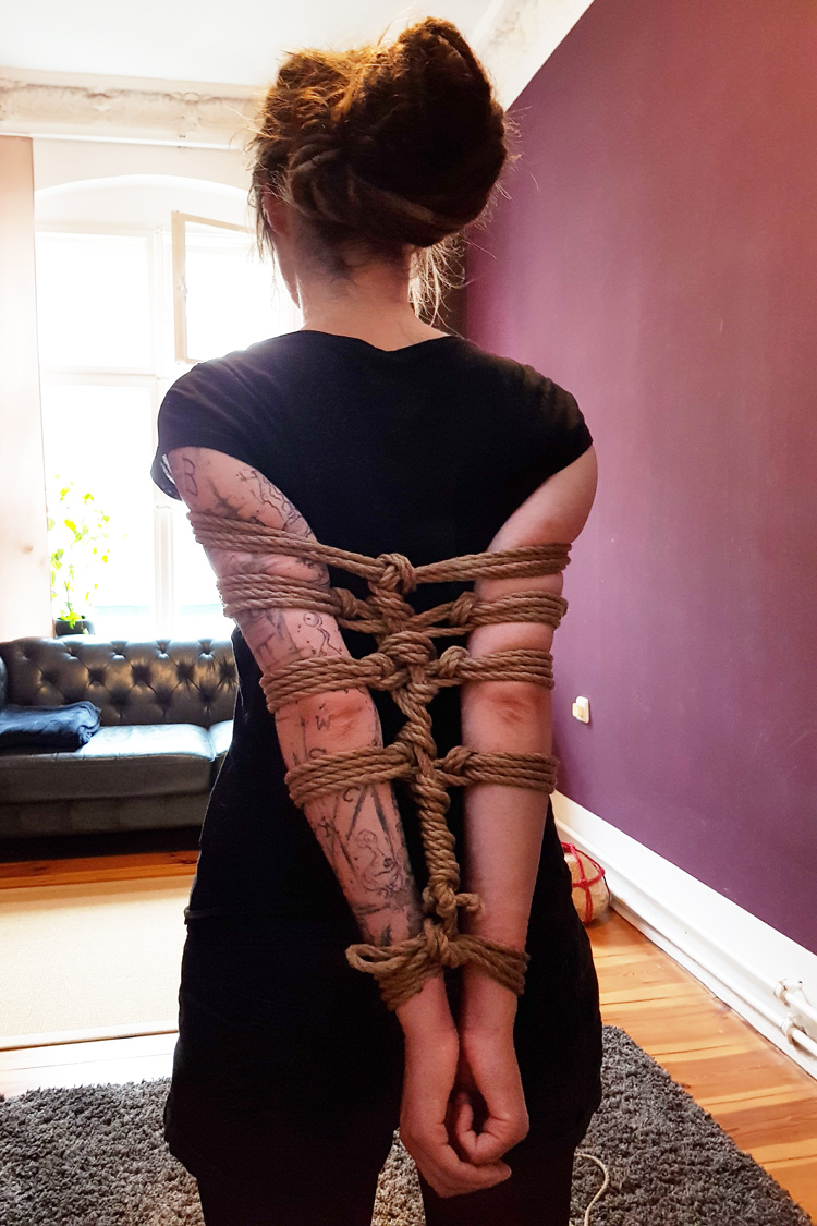 Auf dem Rücken zusammengebundene Arme