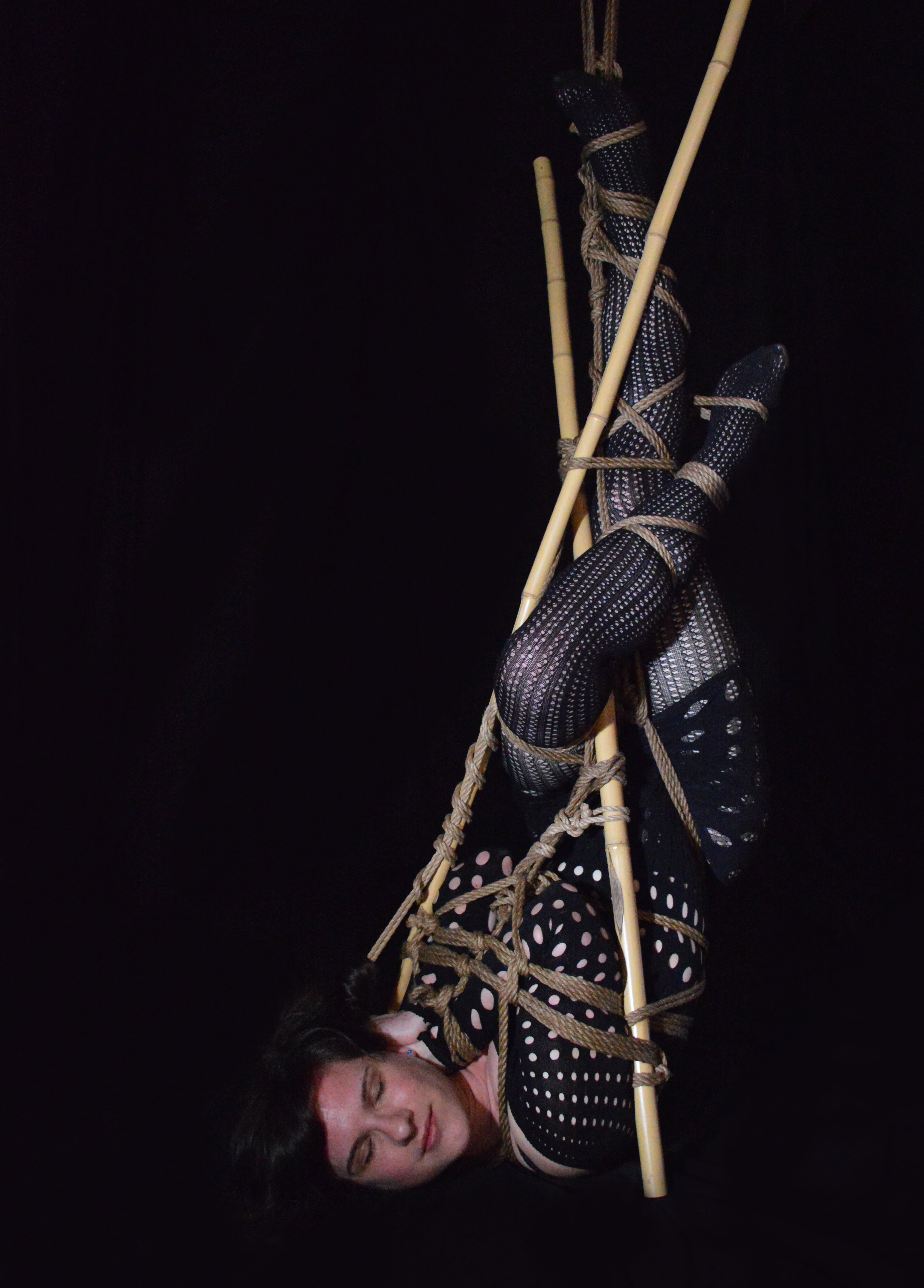 Eine Frau in einer Halbhängung mit Bambusstangen